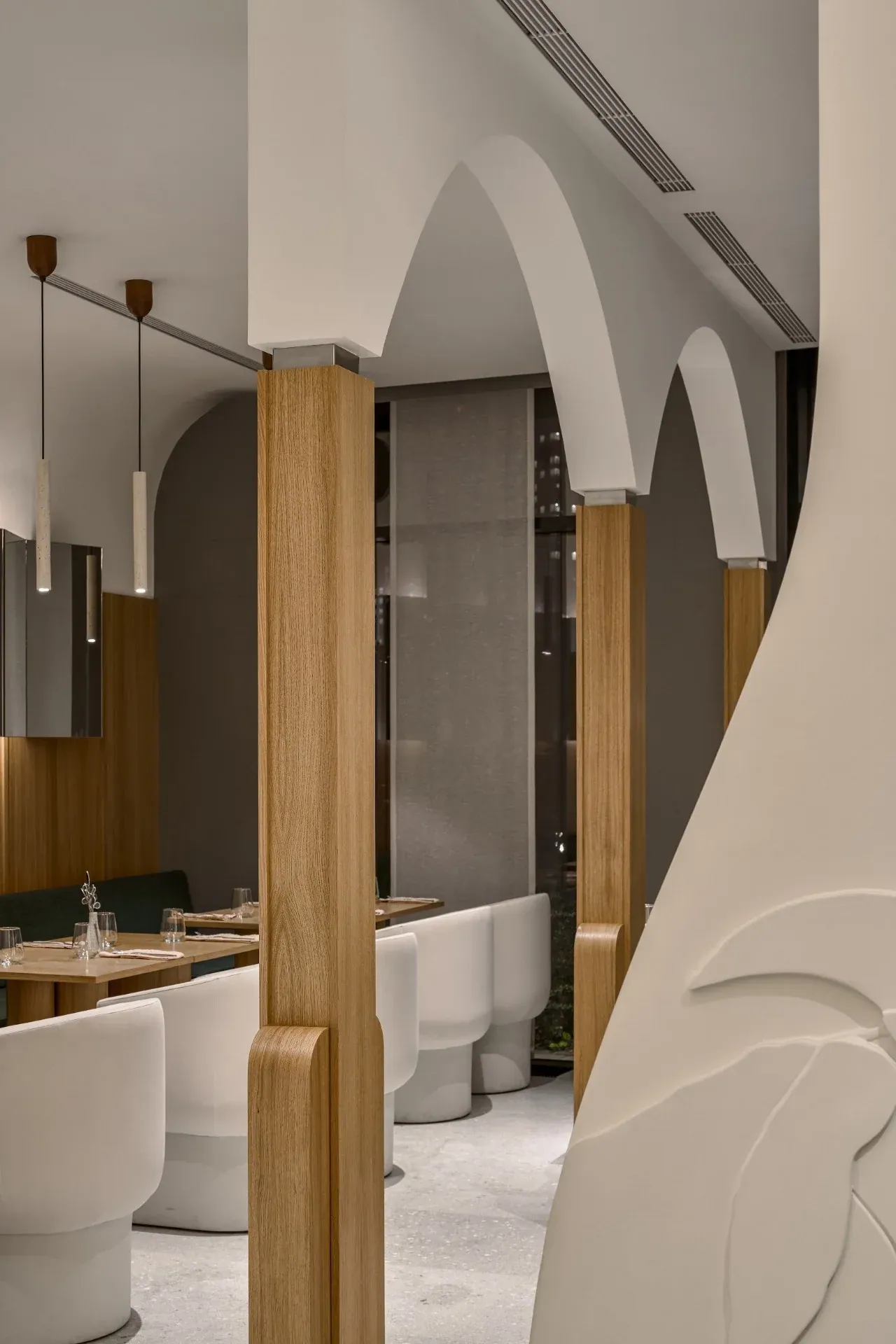 Sculpted white arches between oak-clad pylons, with banquettes and white chairs beyond