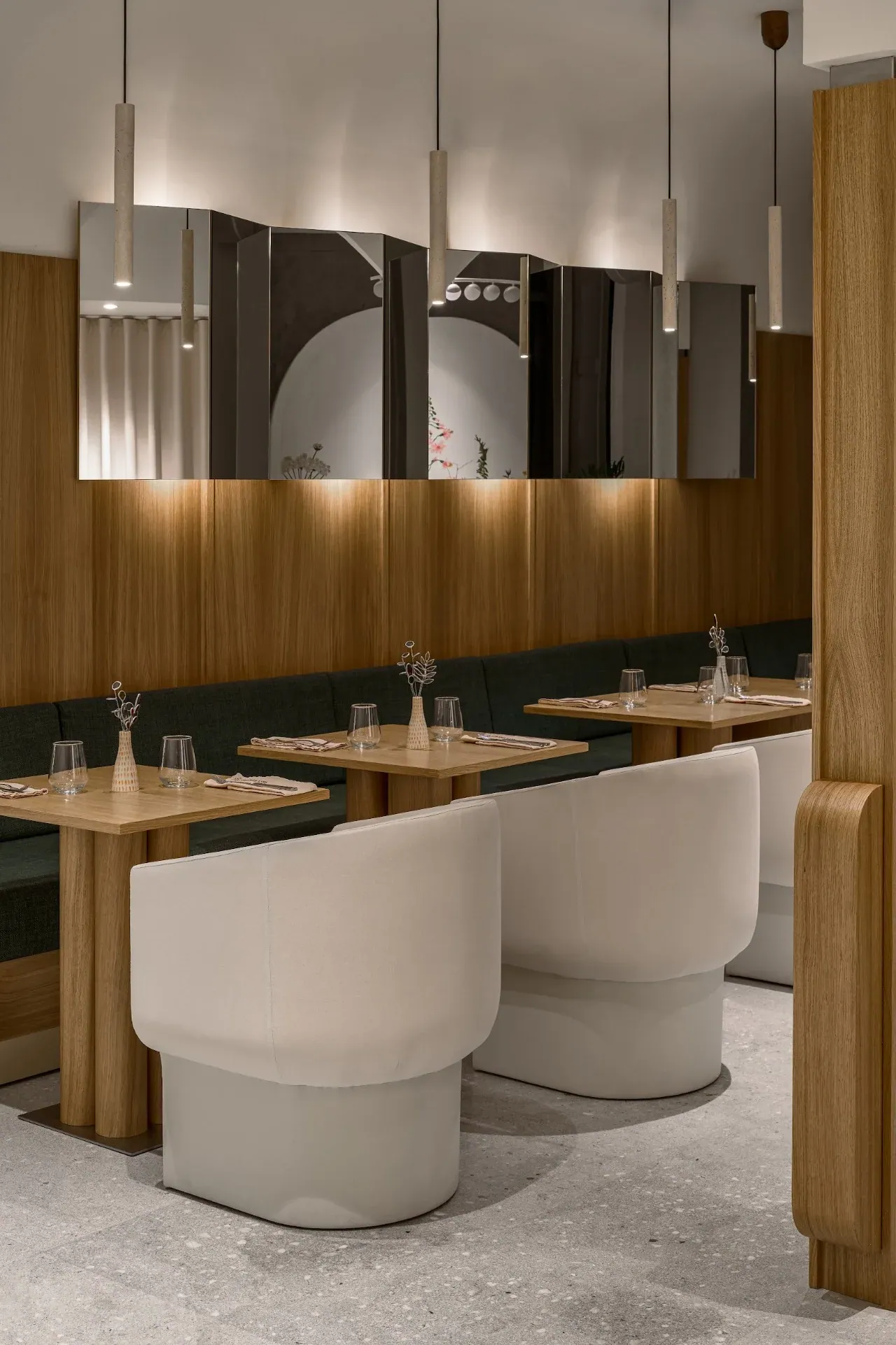 Dining room with oak-clad pylons, pendant lights, banquettes and white chairs