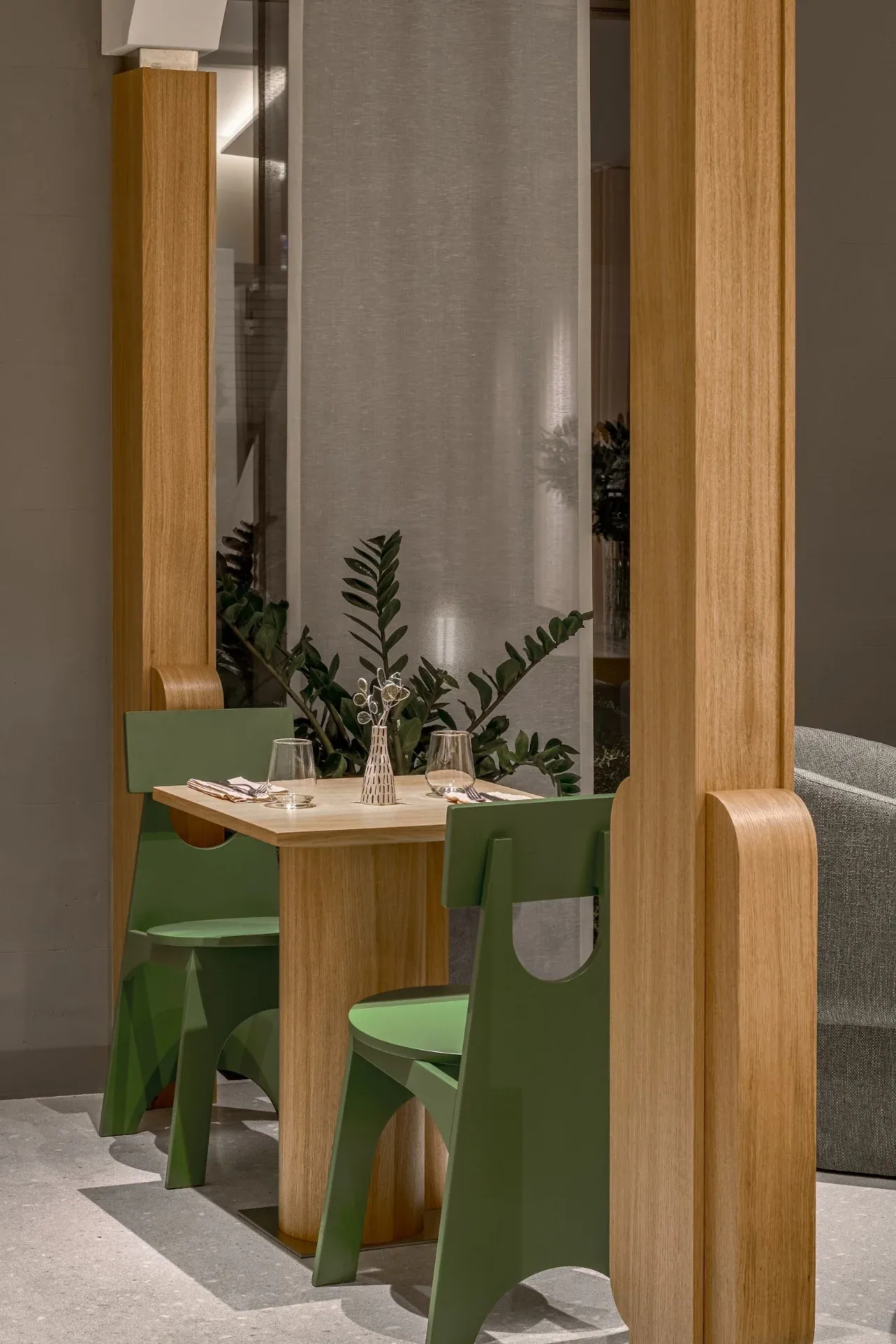 Green chairs and plants between oak-clad pylons